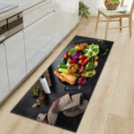 Tapis noir avec bol rempli de légumes et ustensiles de cuisine. Parquet marron clair et meubles de cuisine blancs.