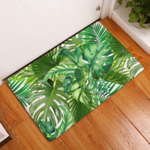 Paillasson imprimé de feuilles de palme vertes sur un parquet devant une porte