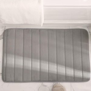 Ce apillasson est gris et à rayures. Il est placé sur le sol d'un salle de bain, devant une baignoire.