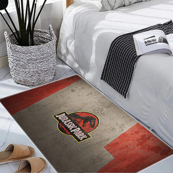 Paillasson Jurassic Park, beige et rouge dans un pièce avec un lit, des chaussons et une plante.
