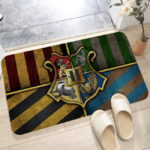 Paillasson harry potter impirmé du blason des quatre mausons de poudlard et leur couleurs. Un paillasson entre deux pièces avec des chaussons dessus.