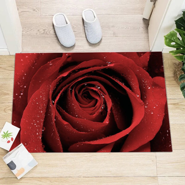 Paillasson imprime d'une rose rouge pose sur du parquet devant une porte avec des chausson a cote et des petites cartes postales