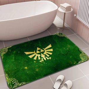 Dans une salle de bain à carrelage ivoire, un paillasson est posé devant une baignoire et à côté de chaussons blancs. Le paillasson est vert foncé avec le symbole de la Triforce en jaune.