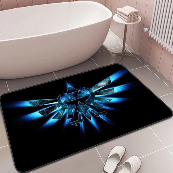 Dans une salle de bain à carrelage ivoire, un paillasson est posé devant une baignoire et à côté de chaussons blancs. Le paillasson est noir avec le symbole de la Triforce en bleu électrique.